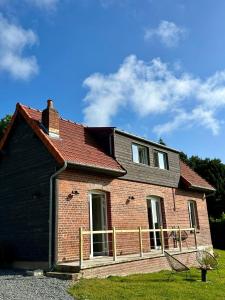 ein Backsteinhaus mit rotem Dach und ein Stuhl in der Unterkunft Carnets de Voyages Maison 4 à 6 personnes in Hautot-sur-Mer
