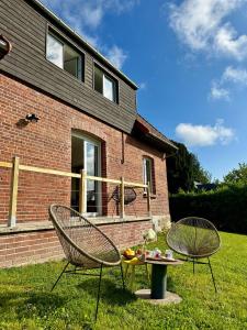 2 Stühle und ein Tisch vor einem Haus in der Unterkunft Carnets de Voyages Maison 4 à 6 personnes in Hautot-sur-Mer