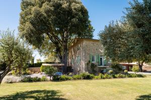 a house with a large tree in front of a yard at La Mouline sublime domaine privatif avec piscine à Pézenas in Pézenas
