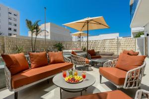 a patio with chairs and tables and an umbrella at Hotel Vibra Yamm Urban - Adults only in San Antonio