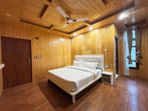 Wood Luxury Hotels Kasauli في كاساولى: غرفة نوم بها سرير ومروحة سقف