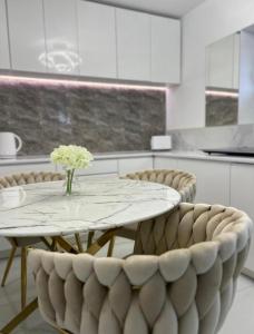 a table and chairs with a vase of flowers on it at GOLD apartment in Święta Katarzyna