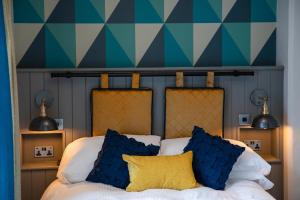 a bedroom with a bed with blue and yellow pillows at The Inn on the Shore in Torpoint +20 photos