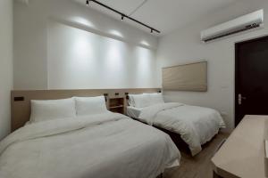zwei Betten in einem Zimmer mit weißen Wänden in der Unterkunft 天盛安家民宿台東一館 in Taitung