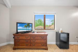 Eine Kommode mit einem Fernseher darauf vor einem Fenster in der Unterkunft Cedar Park Inn in North Stonington