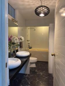 Casa Portada del Sol في La Molina: حمام به مغسلتين ومرحاض وحوض استحمام