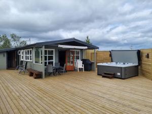 a large deck with a hot tub and a house at Hreiðrið cozy cabin in the countryside in Selfoss