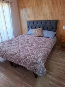a bed with a purple comforter and blue pillows at Cabaña caldera centro in Caldera