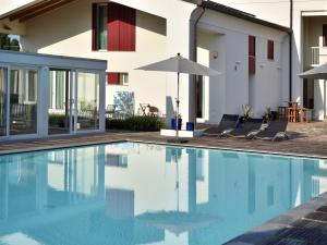 a swimming pool with chairs and an umbrella next to a house at Domus Natura, un'oasi verde tra Padova e Venezia in Vigonza