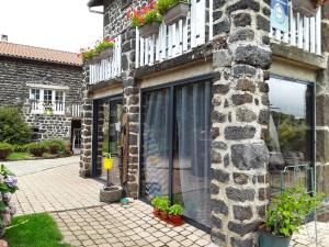 Un edificio de piedra con plantas a los lados. en La Maison d'Amélina, en Séneujols