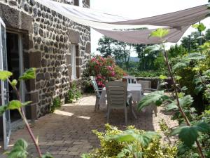 un patio con mesa y sillas bajo una sombrilla blanca en La Maison d'Amélina, en Séneujols 6 fotos más