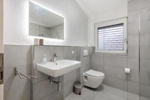 a white bathroom with a sink and a toilet at Motel Ambiente - 4 Zimmer, 2 Bäder in Bad Säckingen +14 photos
