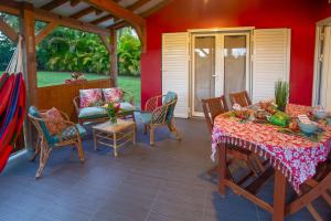 a patio with a table and chairs on a red wall at L'Or des Caraibes in Sainte-Anne