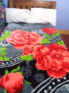 a bed with a black and red floral comforter at Polycap Cottage Home in Murangʼa