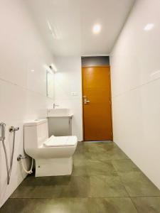 bagno con servizi igienici e porta marrone di Hayashi Resort a Meppādi