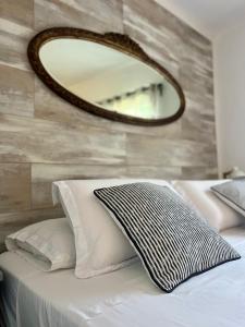 a mirror on a wall above a bed with pillows at Viento Azul Guest House in Punta del Este