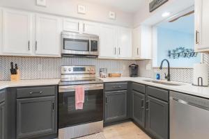 una cucina con mobili bianchi, un lavello e un microonde di Riverfront Condo Walk Downtown Pool Parking a Nashville