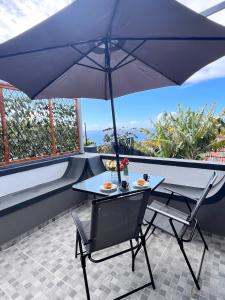 une table et des chaises avec un parasol sur un balcon dans l'établissement Bravas House 1, à Tábua