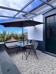 une table et des chaises avec un parasol sur une terrasse dans l'établissement Bravas House 1, à Tábua