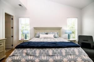 a bedroom with a bed and a chair and windows at Glory Be in Edisto Island