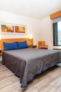 a bedroom with a large bed with blue pillows at Hotel Galerías Express in Tepatitlán de Morelos