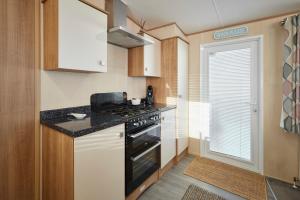 een kleine keuken met een fornuis en een raam bij Host & Stay - Leon's Retreat in Cresswell +16 foto's