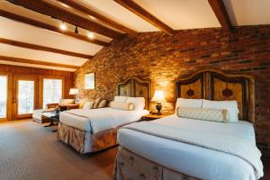 南派恩斯Pine Needles Lodge的一间卧室，有两张床和一堵砖墙