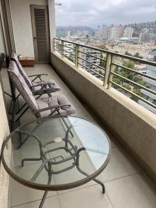 a balcony with two chairs and a glass table at Viña del Mar Department in Viña del Mar +10 photos