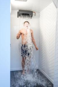 Ein Mann steht in einer Dusche und ist mit Wasser bedeckt in der Unterkunft Country Retreat Sleeping 15 - Bron Menai in Newborough + 73 Fotos