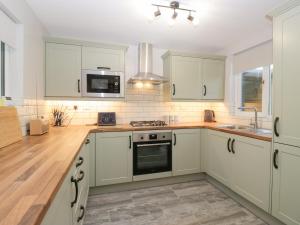 een keuken met witte kasten en een kookplaat oven bij Mables in Silloth