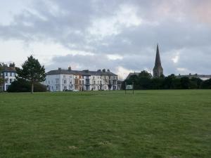 een groot grasveld met huizen en een kerk bij Mables in Silloth
