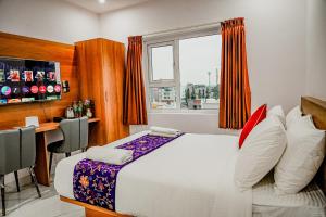 a bedroom with a bed and a desk and a window at Keerthis Grand Hotel near Kempegowda International Airport in Bangalore