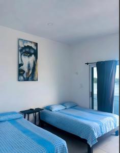 a bedroom with two beds and a painting on the wall at El Amanecer de Chiltepec in Chiltepec