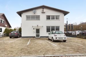 a white house with a car parked in a parking lot at Motel Ambiente 1 - Luxus Studio in Bad Säckingen