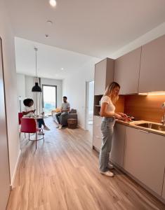 una mujer parada en una cocina junto a un fregadero en Aparto Diagonal Suites, en Esplugues de Llobregat
