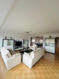 ein Wohnzimmer mit zwei weißen Sofas und einem Fernseher in der Unterkunft Villa Eifelblick Sauna&Wellness Apartment in Heimbach