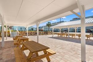 a pavilion with wooden picnic tables and benches at Southwind by Panhandle Getaways in Panama City Beach
