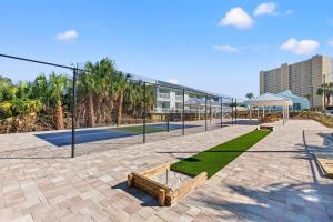 a tennis court with a fence and grass at Southwind by Panhandle Getaways in Panama City Beach