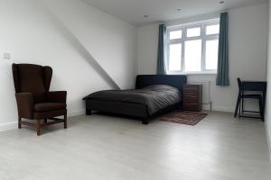 een slaapkamer met een bed, een stoel en een raam bij Rehoboth Housing in Cranford