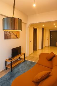 a living room with a large orange bed and a tv at Elegant Ephesus Suites - Hadrian in Selçuk