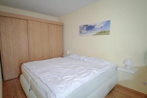 a white bed in a bedroom with a picture on the wall at Vier Jahreszeiten 2-52 in Großenbrode