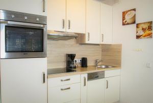 a kitchen with white cabinets and a microwave at Vier Jahreszeiten 2-52 in Großenbrode +10 photos