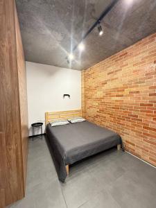 a bedroom with a bed in a brick wall at Loft на Кониського, центр in Dnipro