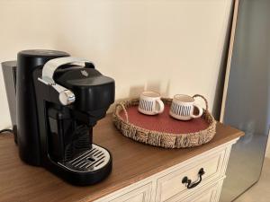una cafetera sentada en un mostrador con dos tazas en Le Mas des Vignes en Drome provençale, en Rochegude