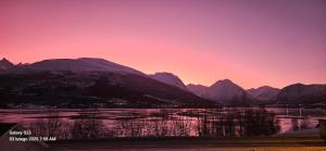 una puesta de sol sobre una cordillera con un cuerpo de agua en Ramfjord Apartment 2, en Tromsø