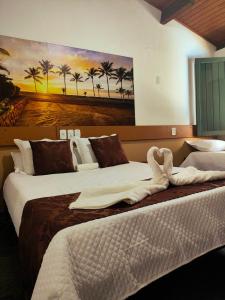 two beds in a hotel room with a painting on the wall at Hotel Trevo do Porto in Porto Seguro +246 photos