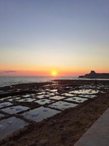 a person standing on the beach at sunset at Salty Sun Seafront Penthouse in Marsalforn