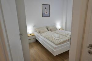 a small bedroom with a white bed with two lamps at Apartman Anita in Kupres