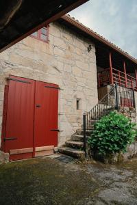 eine rote Tür an einem Steingebäude mit Treppe in der Unterkunft Casa do Botas in Sober