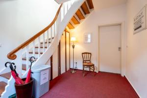 哥根巴赫Boutique Suites by K A M E L U的一条走廊，里面有楼梯，铺着红地毯，还有一把椅子。